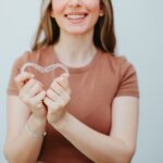 woman holding invisalign clear aligners, does my insurance cover invisalign