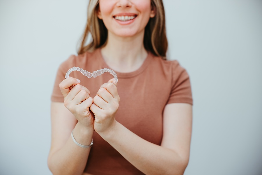 woman holding invisalign clear aligners, does my insurance cover invisalign